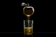 an apple made from liquid and splashes pouring out into a jar of apple juice