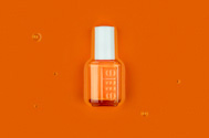 bottle of essie nail polish in a pool of liquid paint